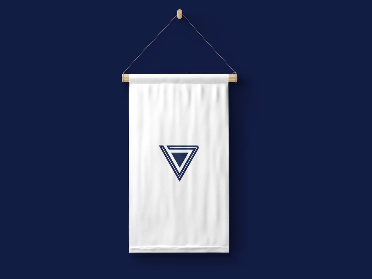 Un lienzo blanco colgado con una barra de madera presenta un diseño de triángulo azul en el centro. El fondo es de color azul oscuro, lo que resalta el contraste entre el lienzo y el diseño. Este elemento visual es representativo de la marca 'punto clave'.
