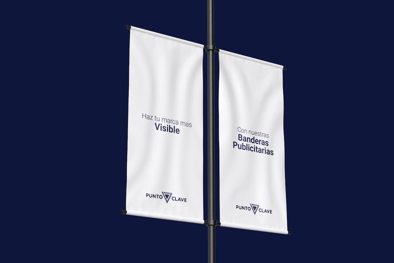 Se observan dos banderas publicitarias colgadas, con fondo blanco y textos en azul. Una bandera dice 'Haz tu marca más Visible', y la otra 'Con nuestras Banderas Publicitarias', ambas de la marca 'punto clave'. El fondo es de color oscuro.