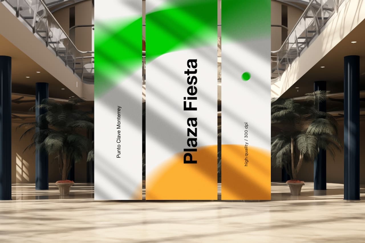 Un espacio interior amplio con tres paneles verticales que presentan los colores verde, naranja y blanco. En el panel central destaca el texto 'Plaza Fiesta' en negro, mientras que en los laterales se puede leer 'Punto Clave Monterrey' y una nota sobre calidad de impresión. El ambiente incluye plantas y un diseño moderno.