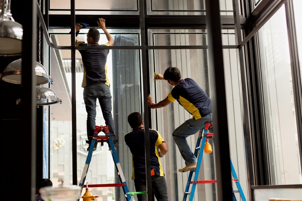 Personas colocando viniles impresos en ventanas de un espacio comercial