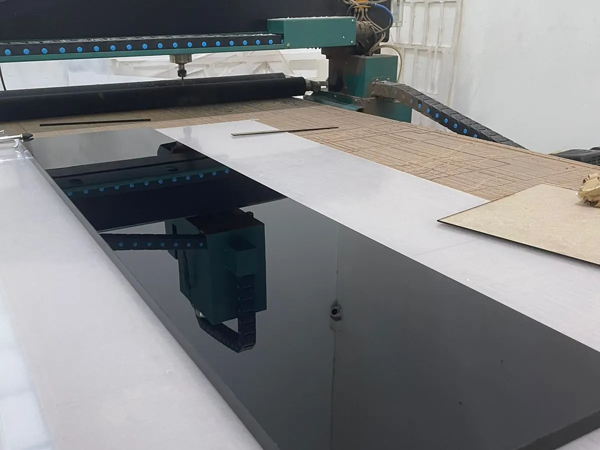 Lámina de acrílico negro sobre la mesa del router CNC del taller antes de cortar
