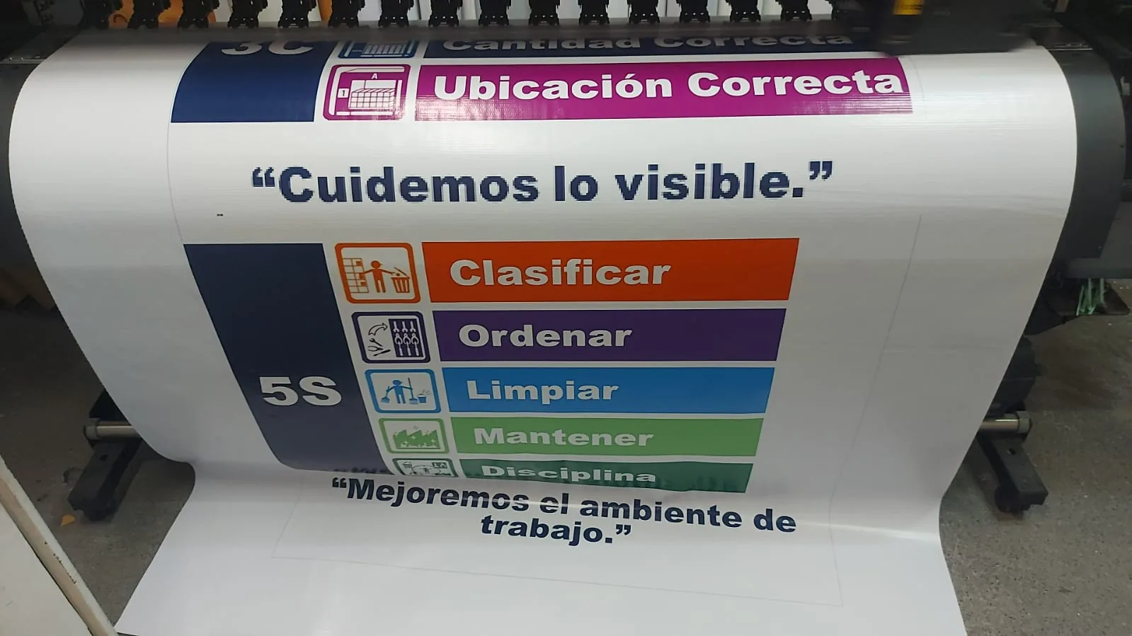 Lona impresa a color saliendo del plóter de gran formato en el taller de Punto Clave